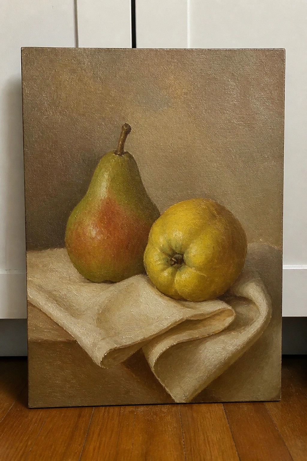 Still life painting of green pear and yellow fruit on draped beige cloth.
