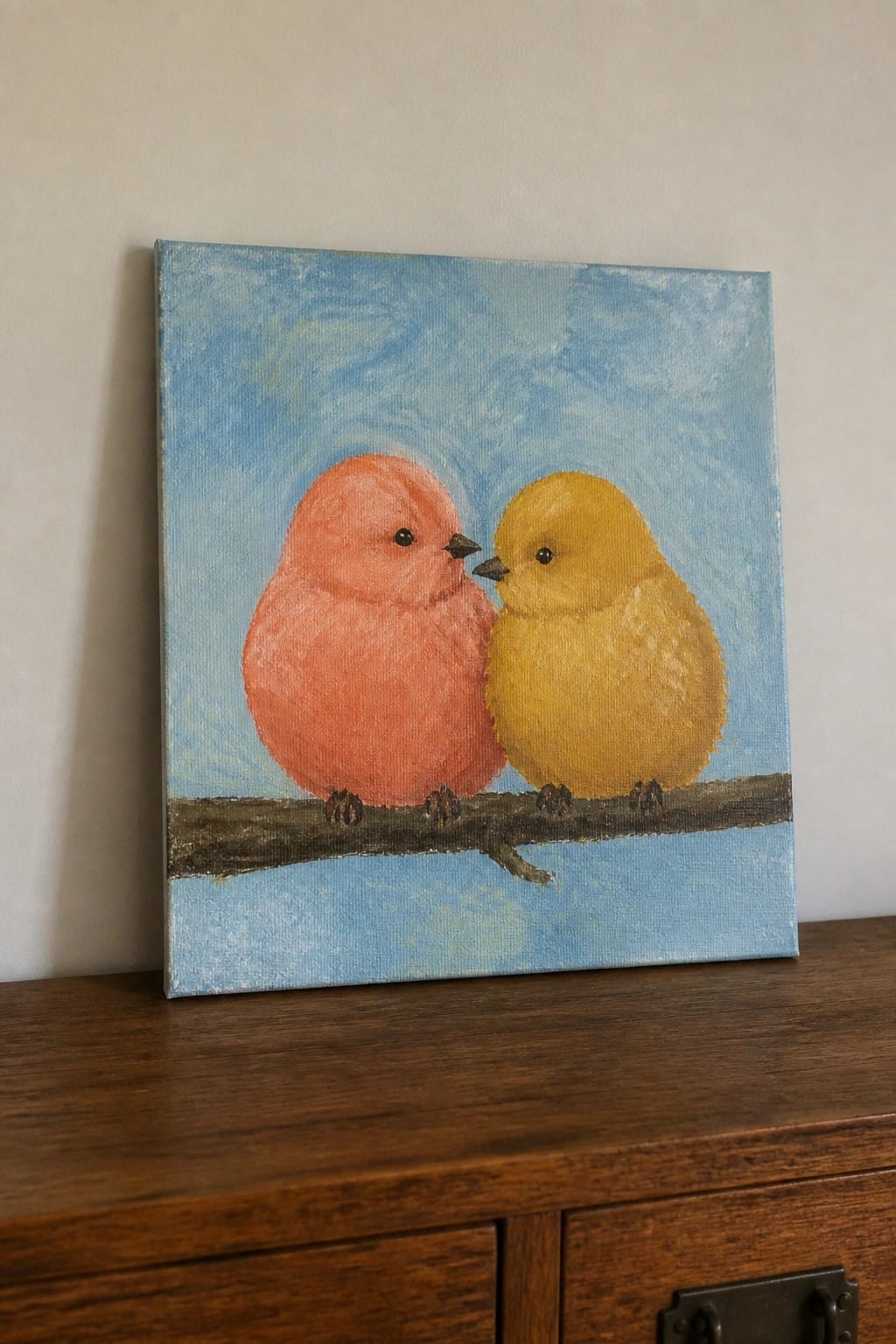 Painting of pink and yellow birds perched close on a branch against blue sky