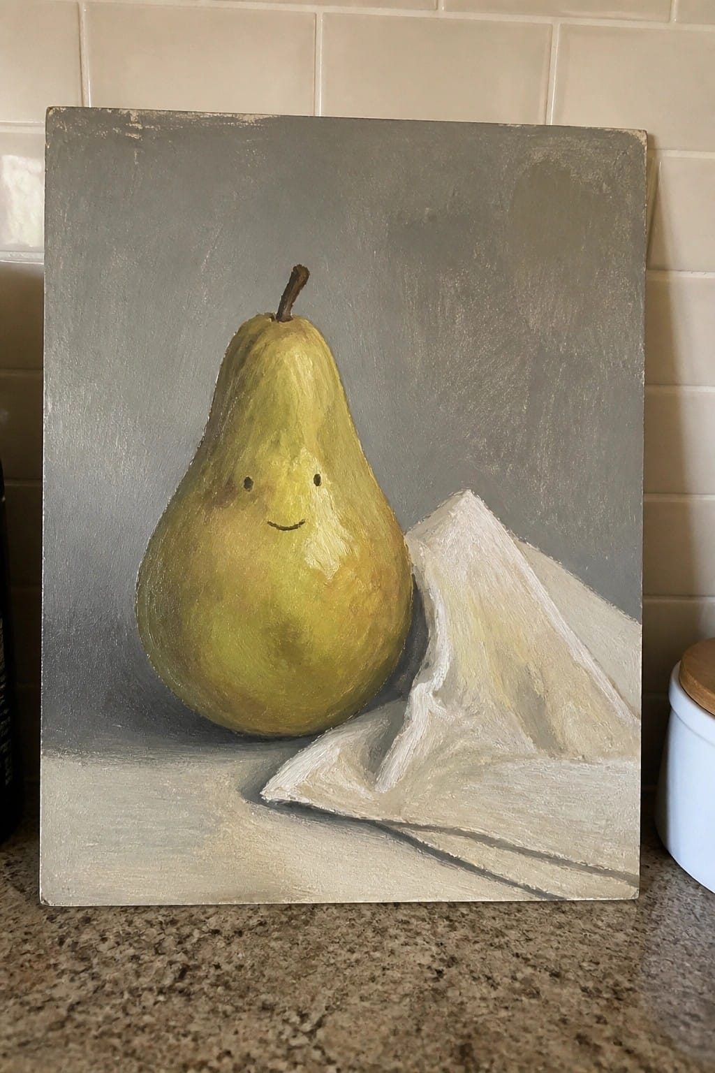 Acrylic painting of a smiling yellow pear beside a white cloth on gray background