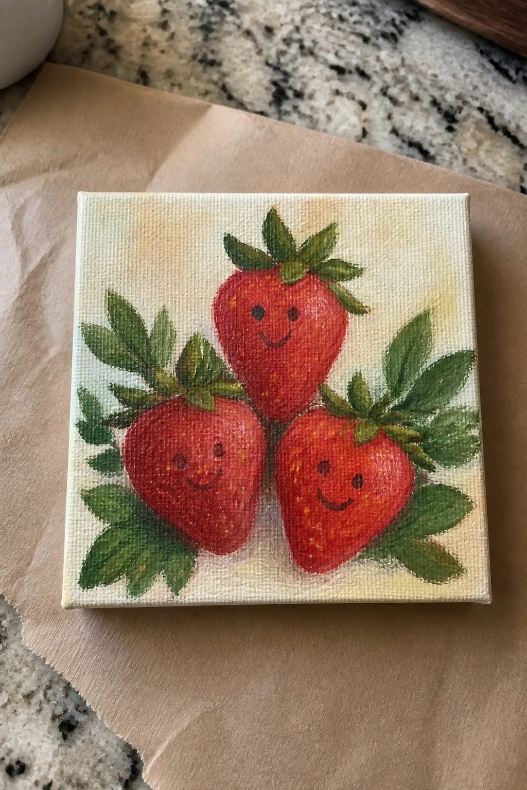 Three smiling red strawberries with green leaves on small canvas painting