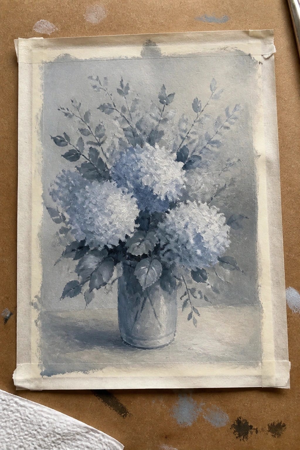 Watercolor still life of blue and white hydrangeas in a gray vase, taped to paper