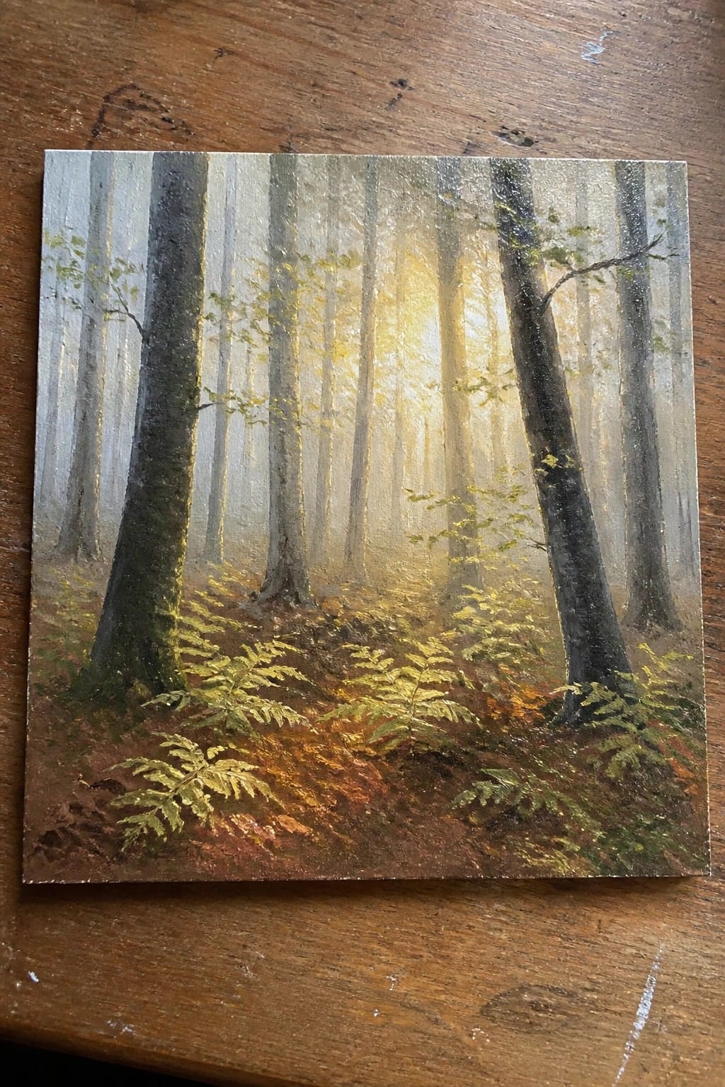 Misty forest painting with tall trees, golden sunlight rays, and ferns on the ground.