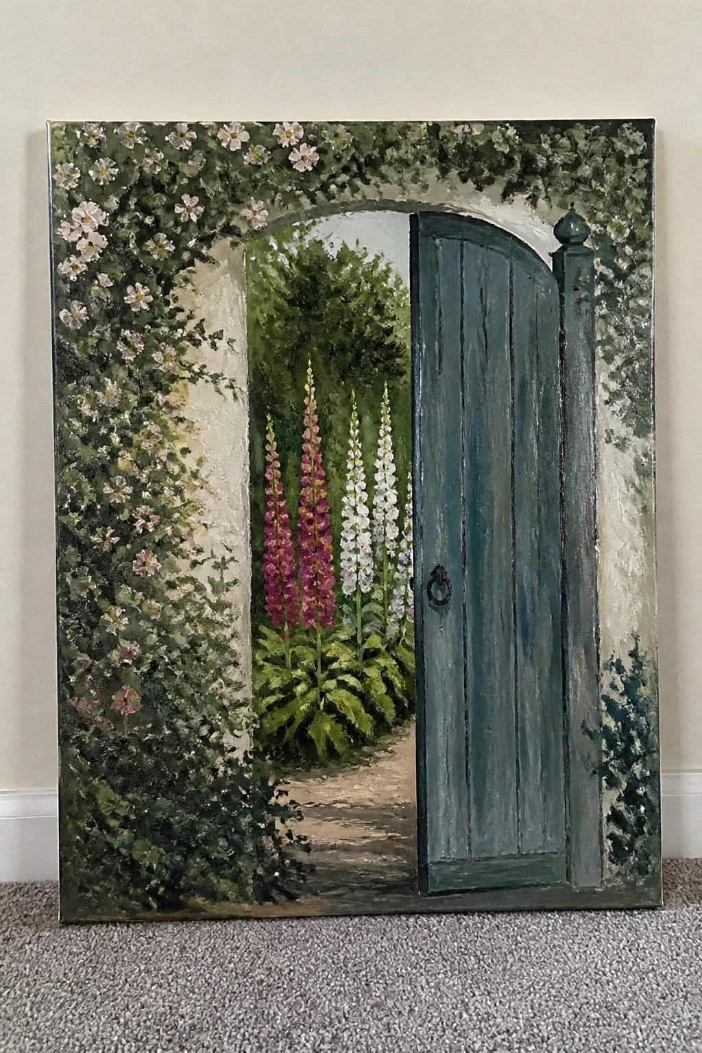 Open teal wooden gate in archway draped with white flowers and vines.