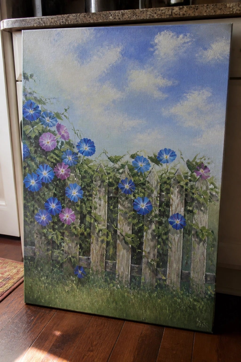 Blue and purple morning glories climbing a weathered wooden picket fence under a cloudy sky.