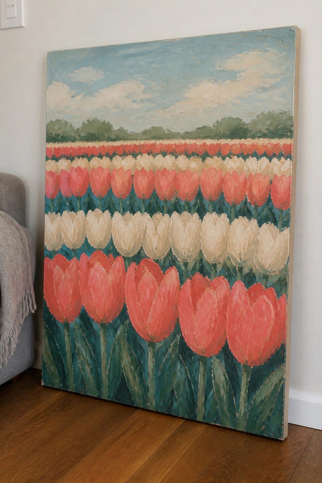 Painting of red and white tulips leaning against wall on wooden floor