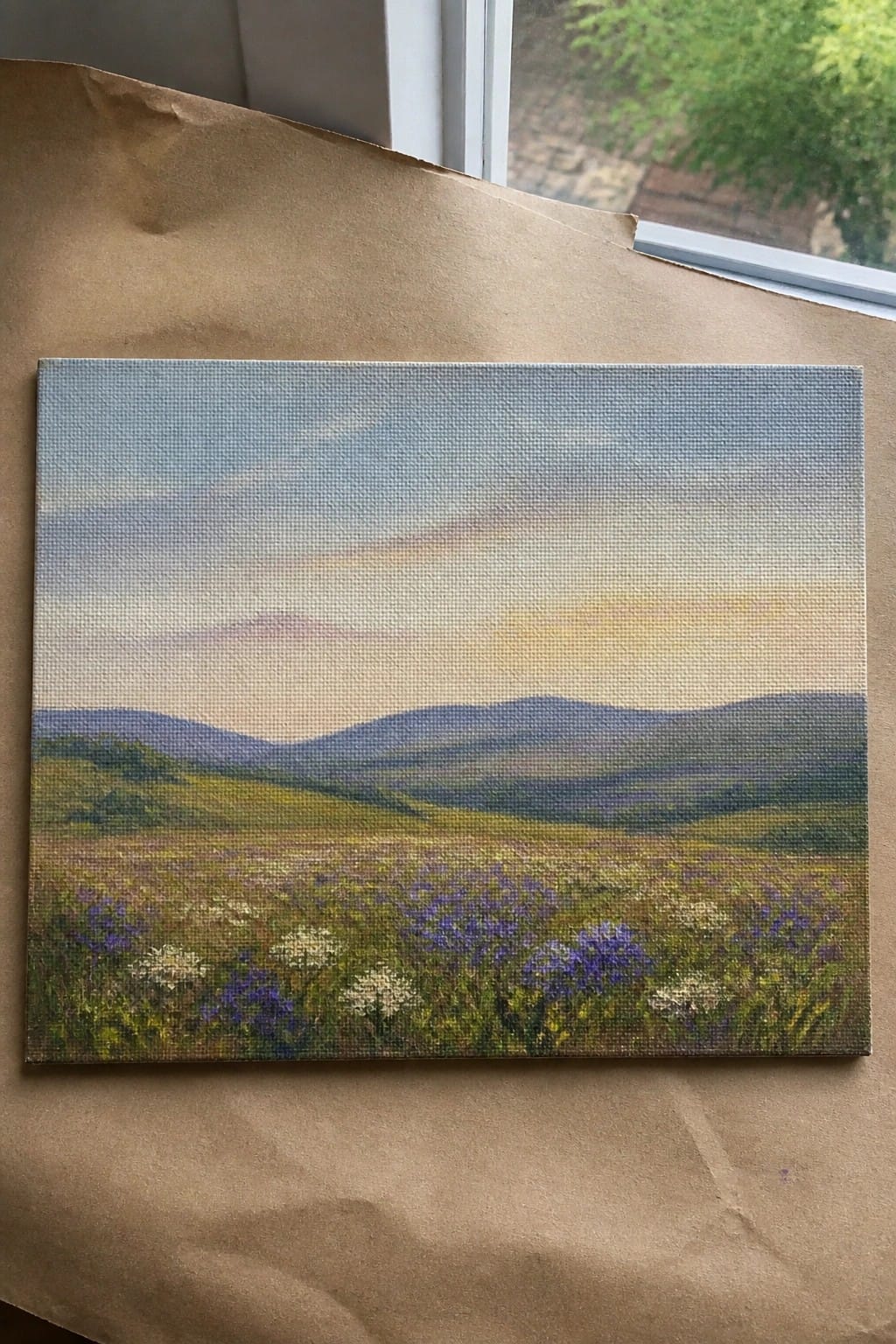 Canvas painting of wildflower meadow with purple blooms and distant blue hills at sunset