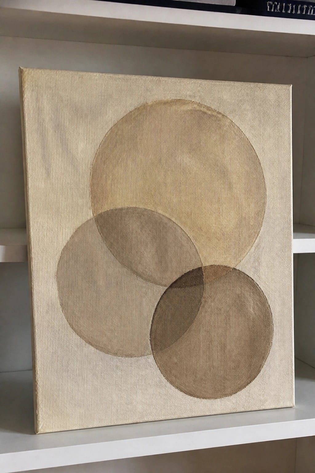 Minimalist canvas with three overlapping circles in neutral brown tones on shelf