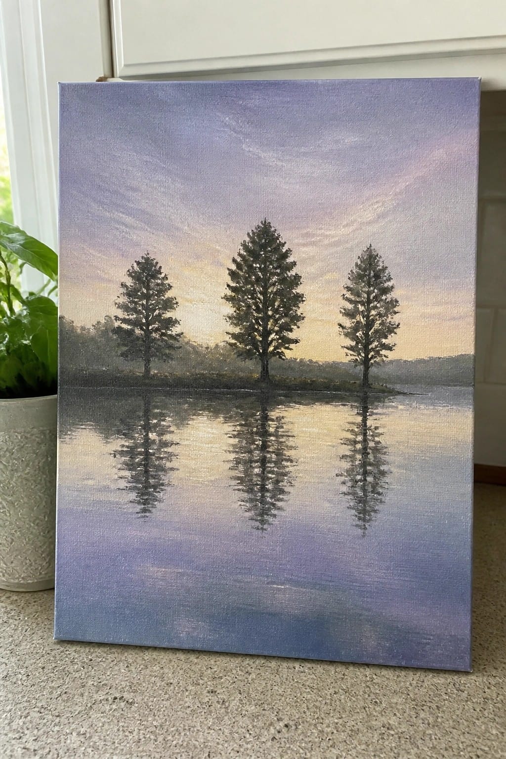 Three tall trees reflected in still water beneath a pastel purple sunset sky