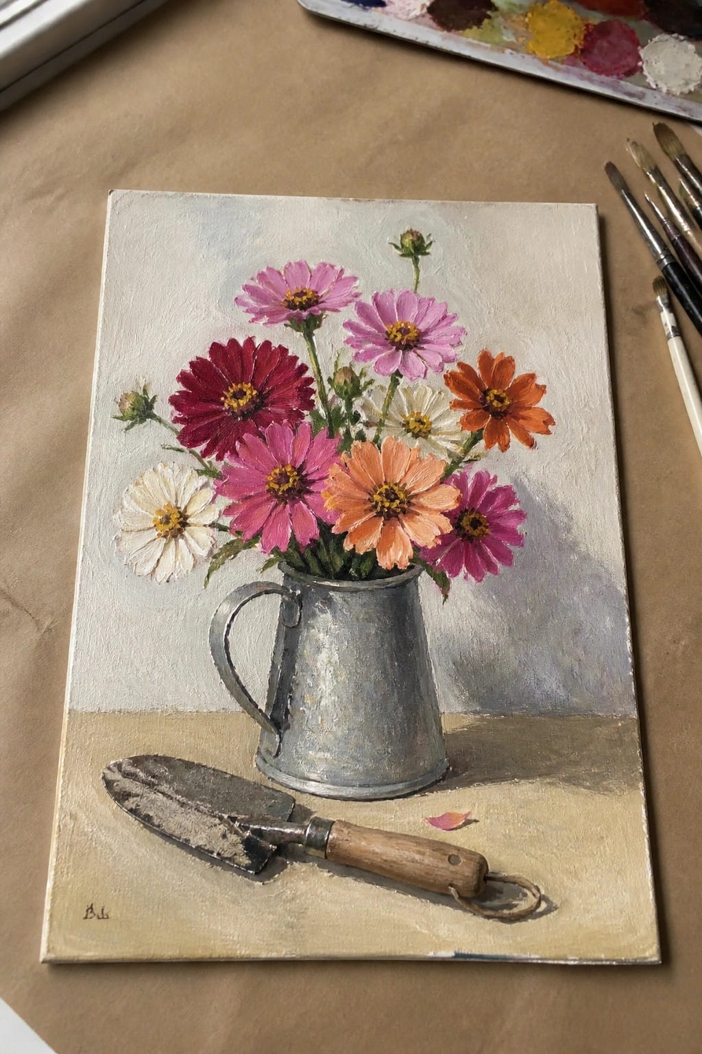 Still life painting of colorful flowers in metal pitcher beside garden trowel