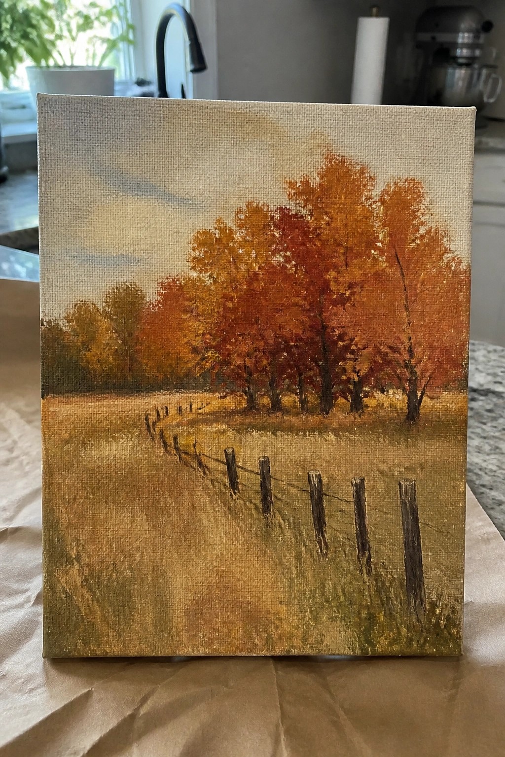 Impressionistic canvas painting of autumn trees with orange leaves and wooden fence