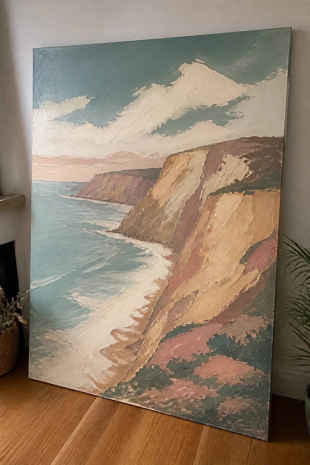 Large impasto painting of colorful cliffs by turquoise sea leaning on wooden floor