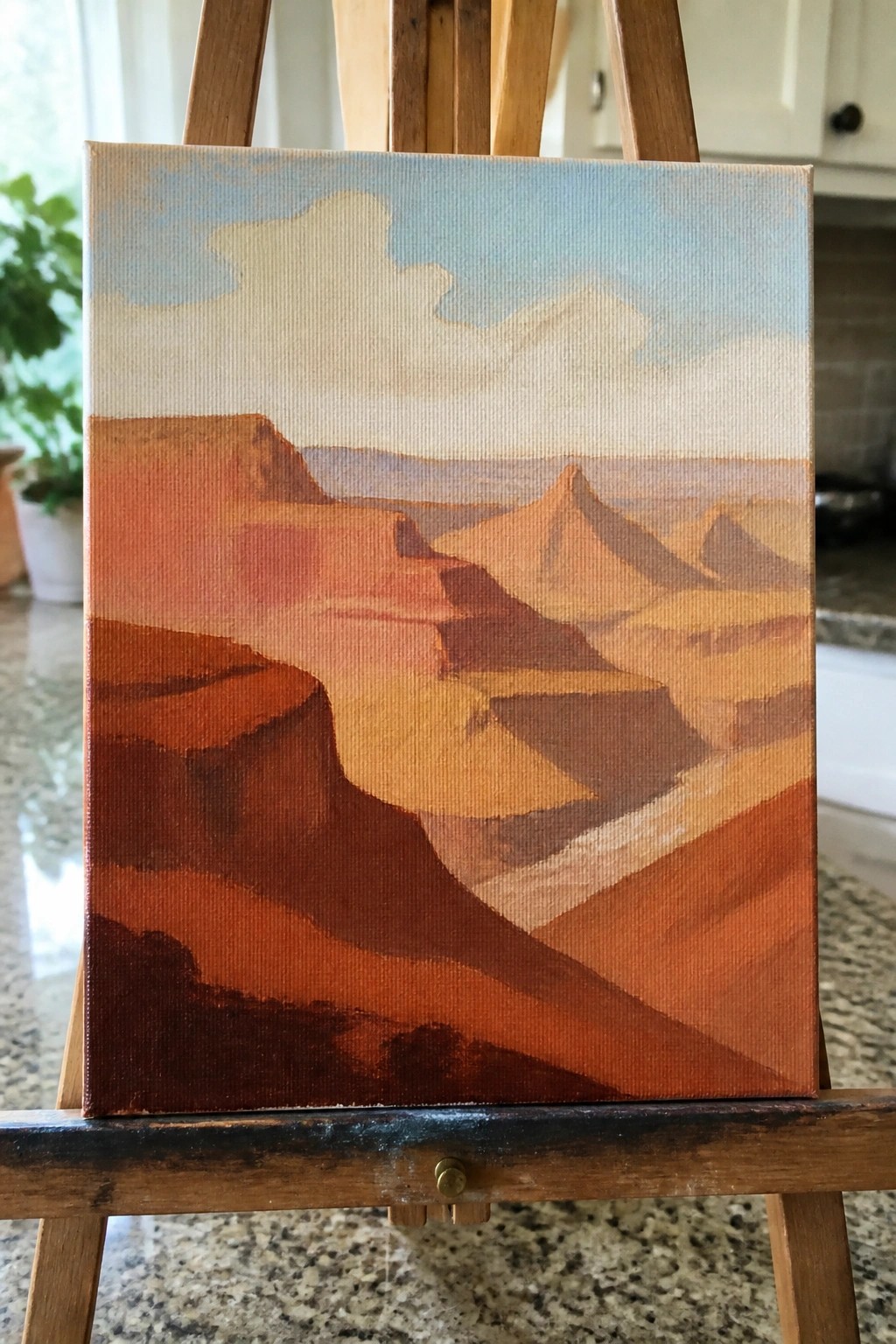 Oil painting of red-orange canyon mesas under a cloudy blue sky on wooden easel.