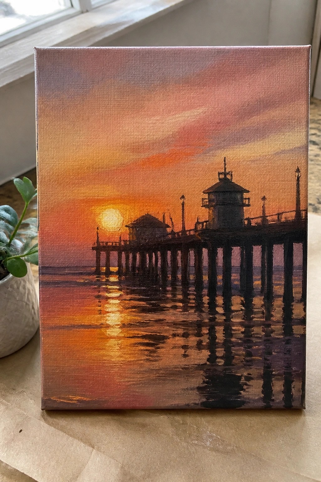 Canvas painting of silhouetted pier at vibrant orange ocean sunset with reflections
