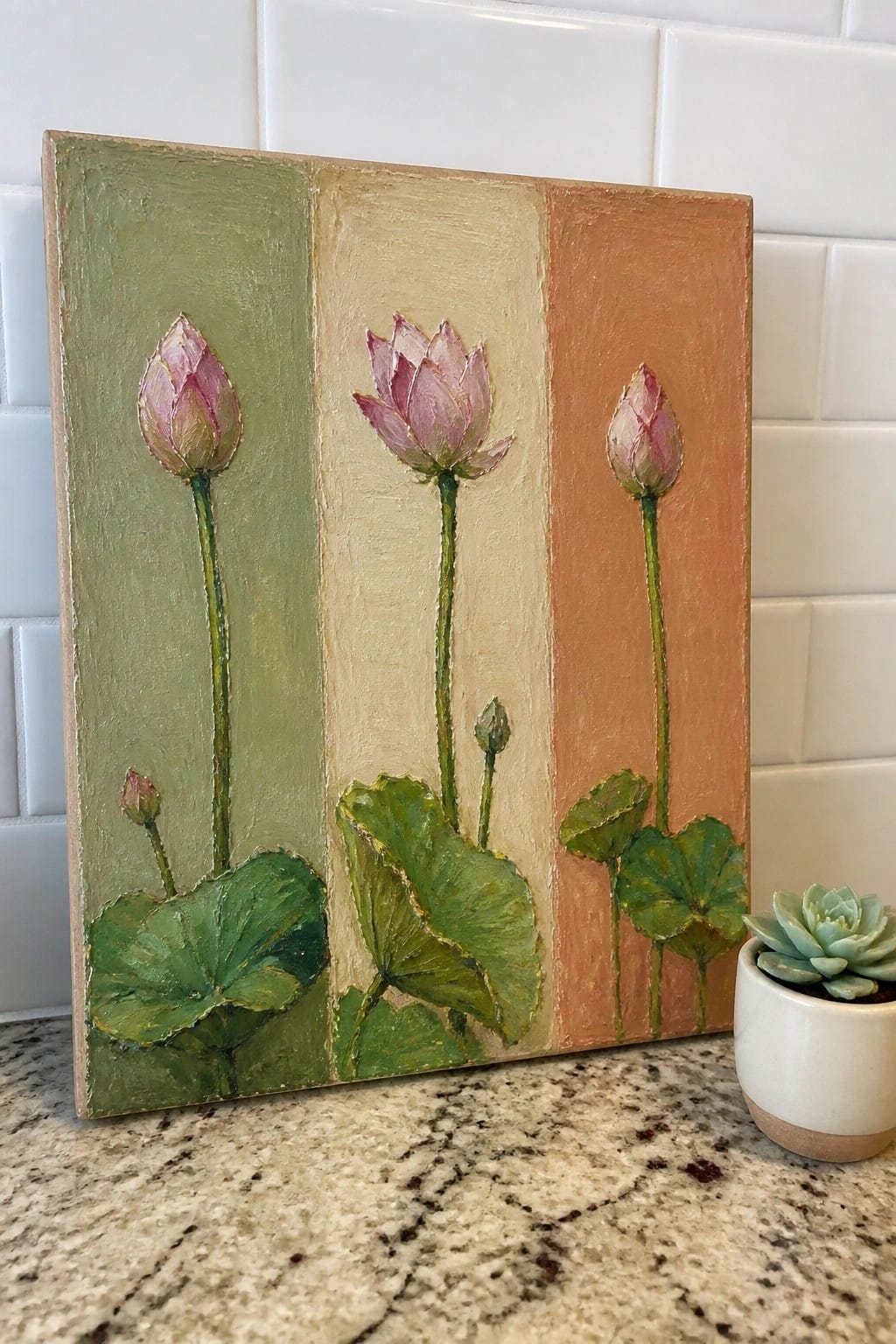 Three pink lotus flowers on green, beige, and orange striped canvas beside potted succulent