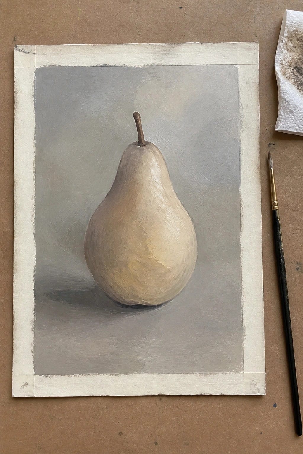 Realistic painting of a tan pear on gray canvas beside a paintbrush.