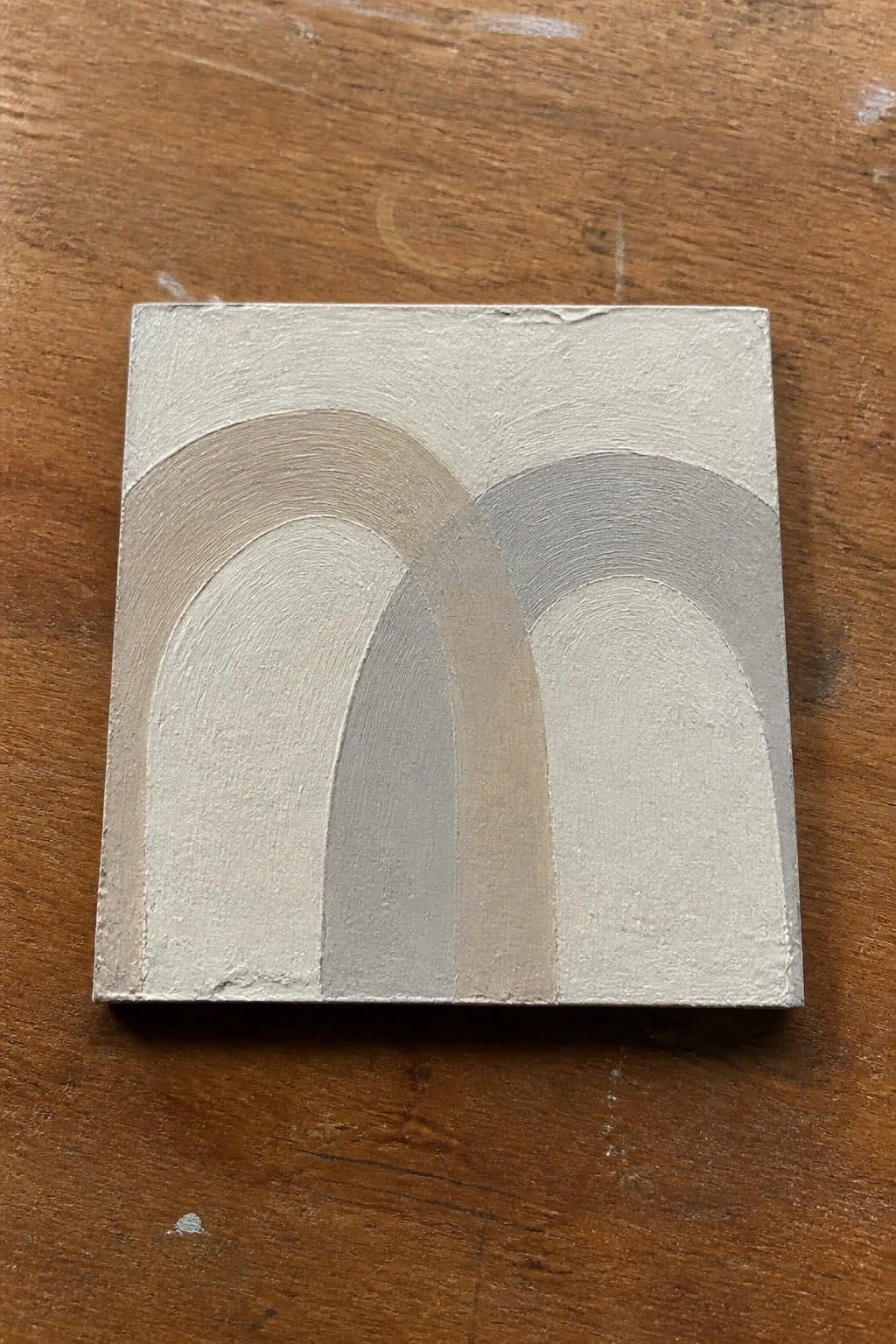 A small square oil painting on wood with overlapping arched shapes in shades of beige, gray, and off-white.
