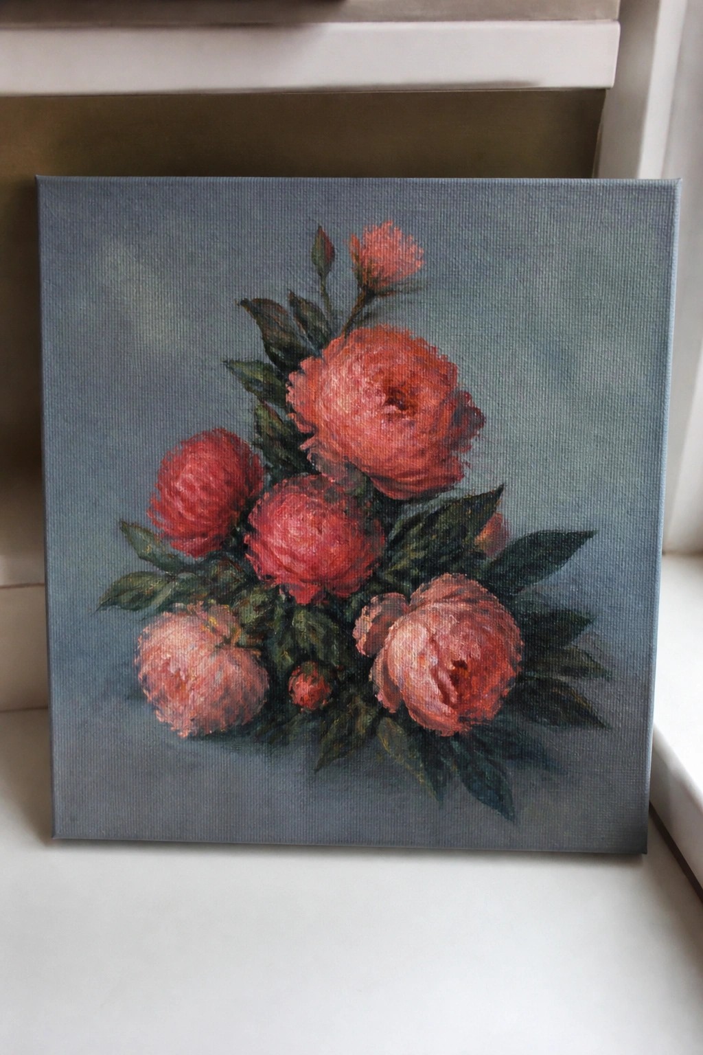 Oil painting of red peonies with green leaves on blue-gray canvas.