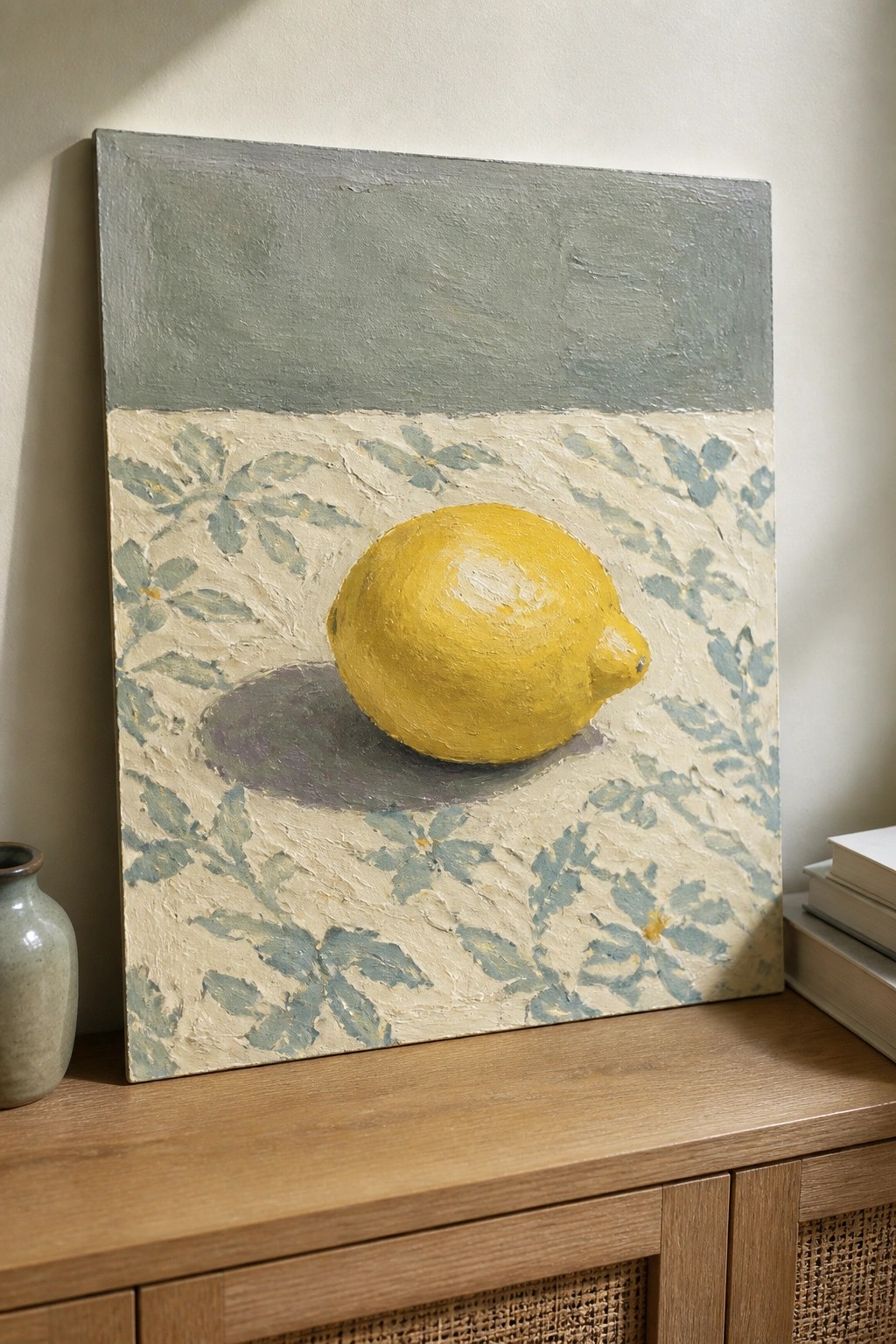 Yellow lemon still life painting on patterned fabric atop wooden cabinet