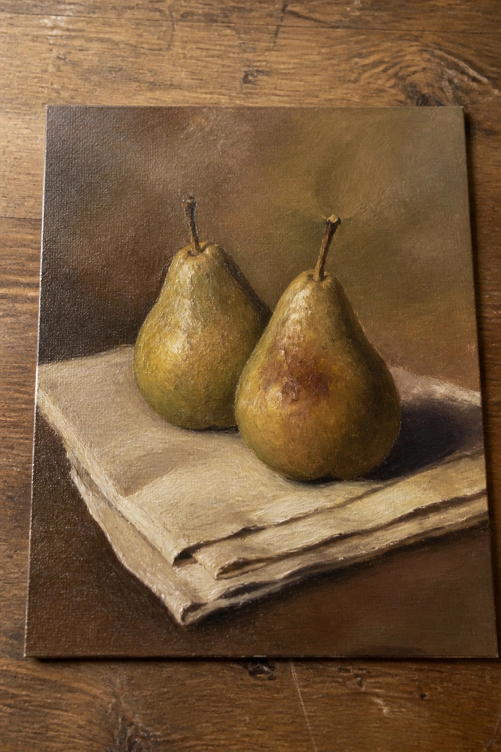 Two pears on stacked papers over dark wood in realistic oil painting.