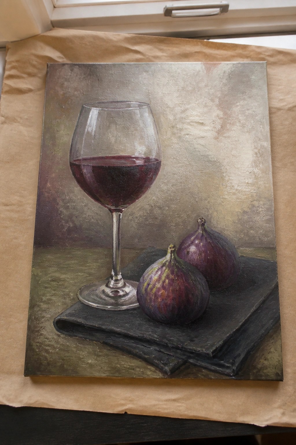 Realistic painting of red wine glass beside two purple figs on black cloth