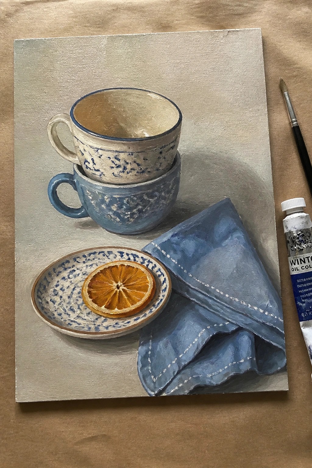 Still life oil painting of stacked cups, dried orange on saucer, blue cloth.