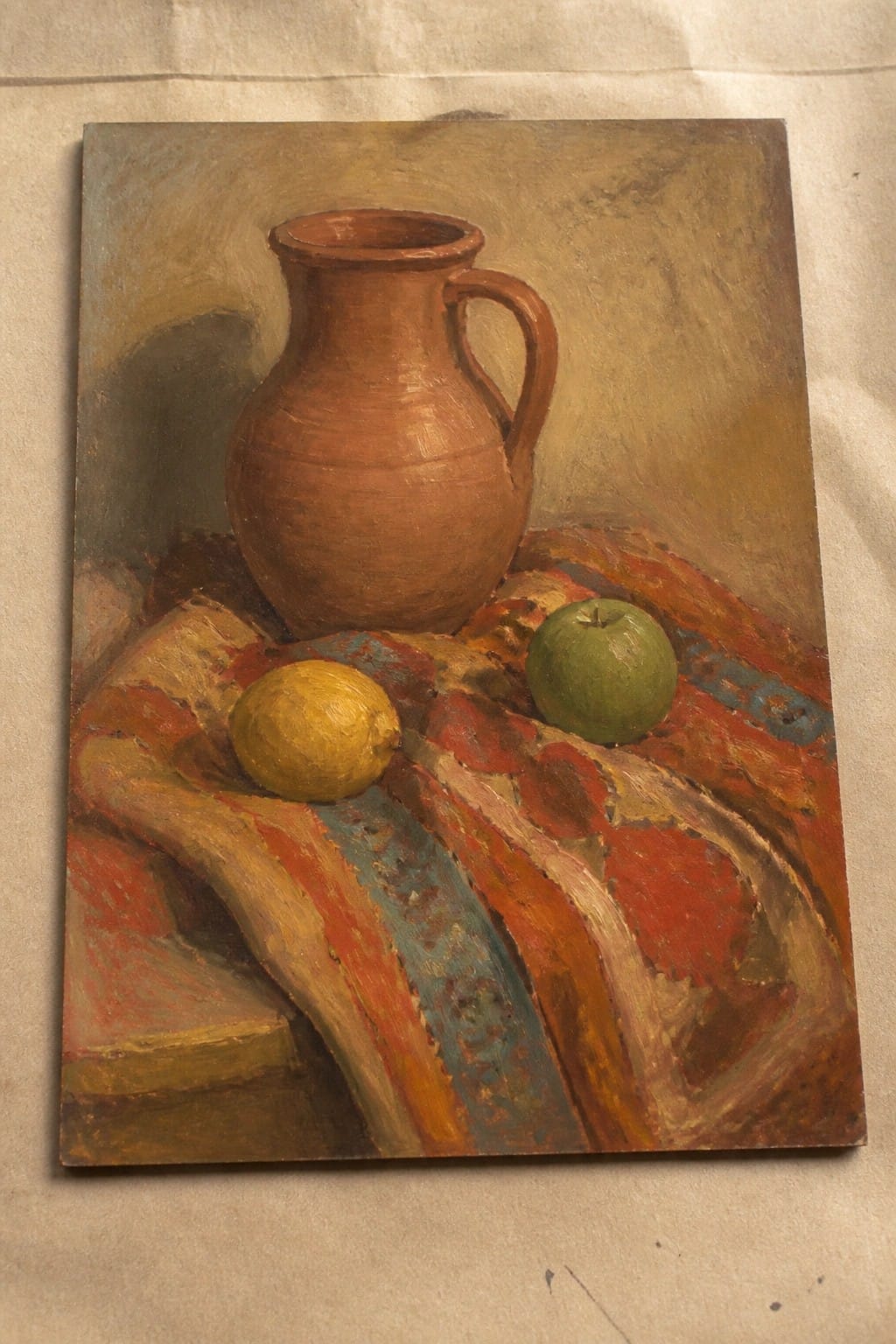 Terracotta pitcher with lemon and green apple on vibrant red patterned cloth.