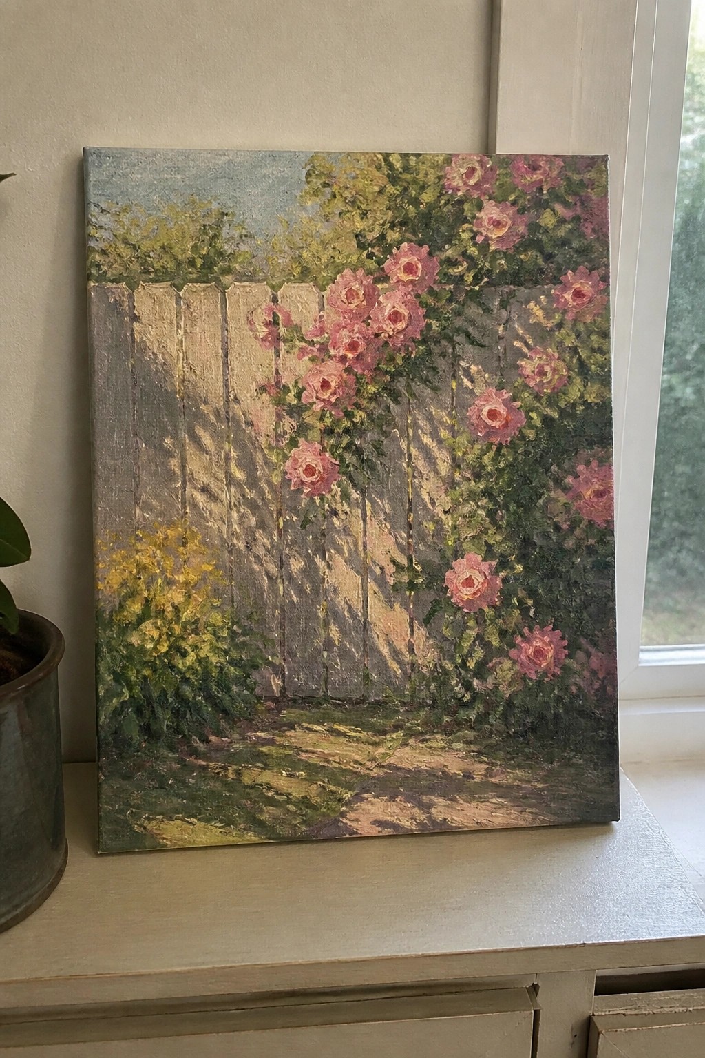Pink roses climb a vine-covered wooden fence amid green foliage and sunlight.
