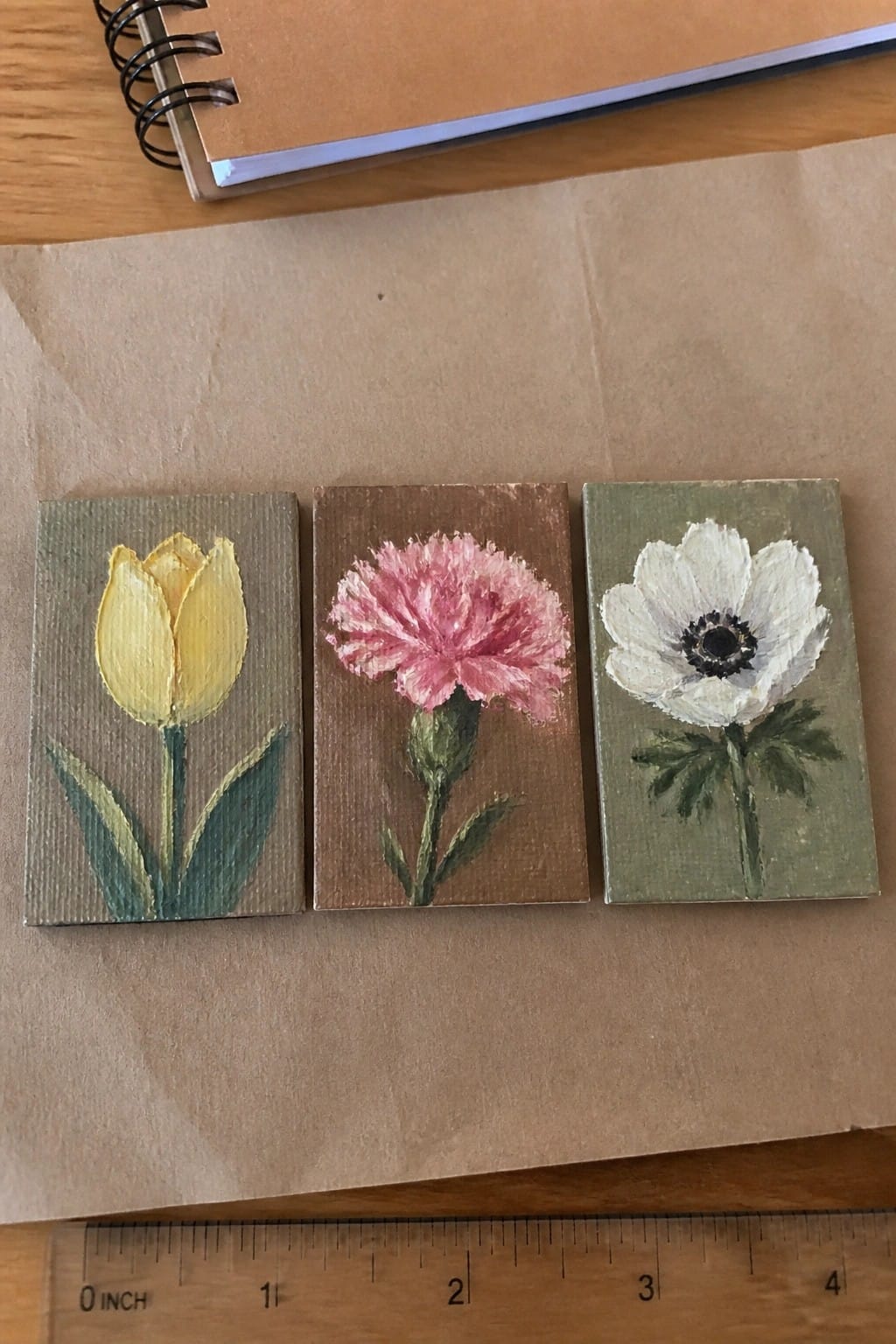 Three small flower paintings of tulip, carnation, and anemone beside a ruler
