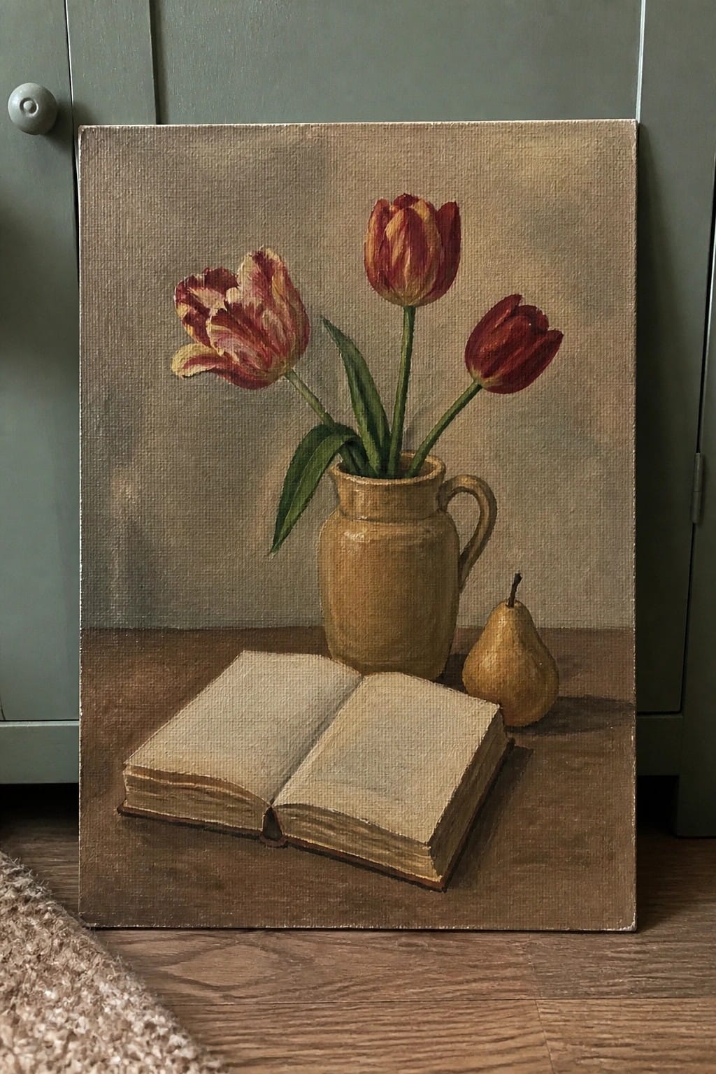 Three red tulips in a ceramic jug beside an open book and yellow pear.