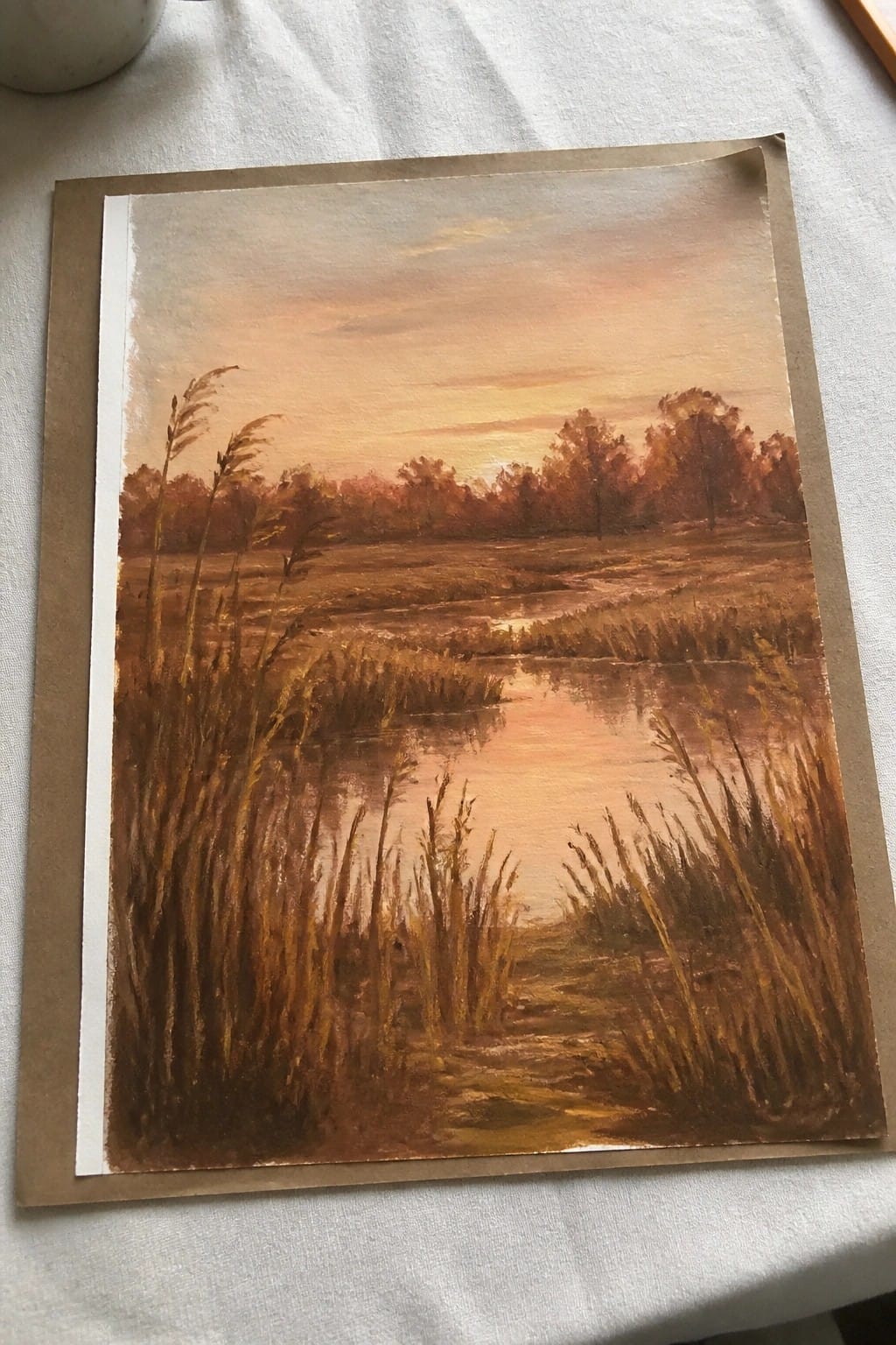 Warm-toned painting of sunset over marsh with tall golden reeds and reflective water.