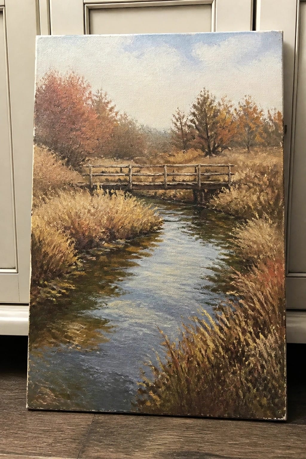 Oil painting of wooden bridge over winding stream amid autumn trees and grasses