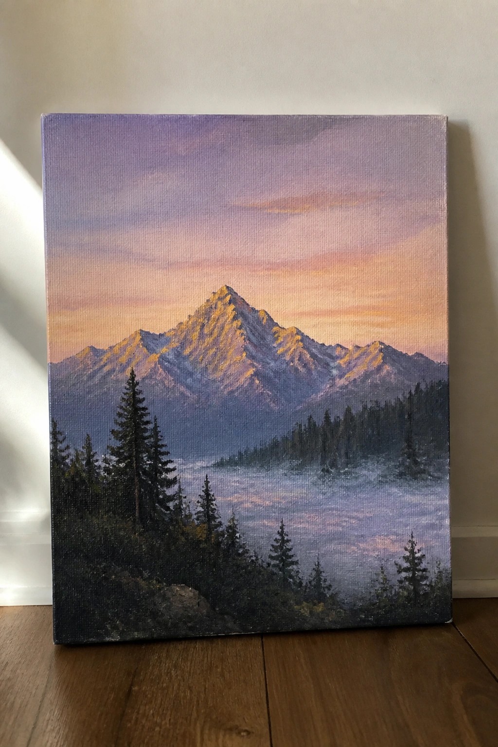 Painting of golden-lit mountain peaks at sunset above misty valley with pine trees