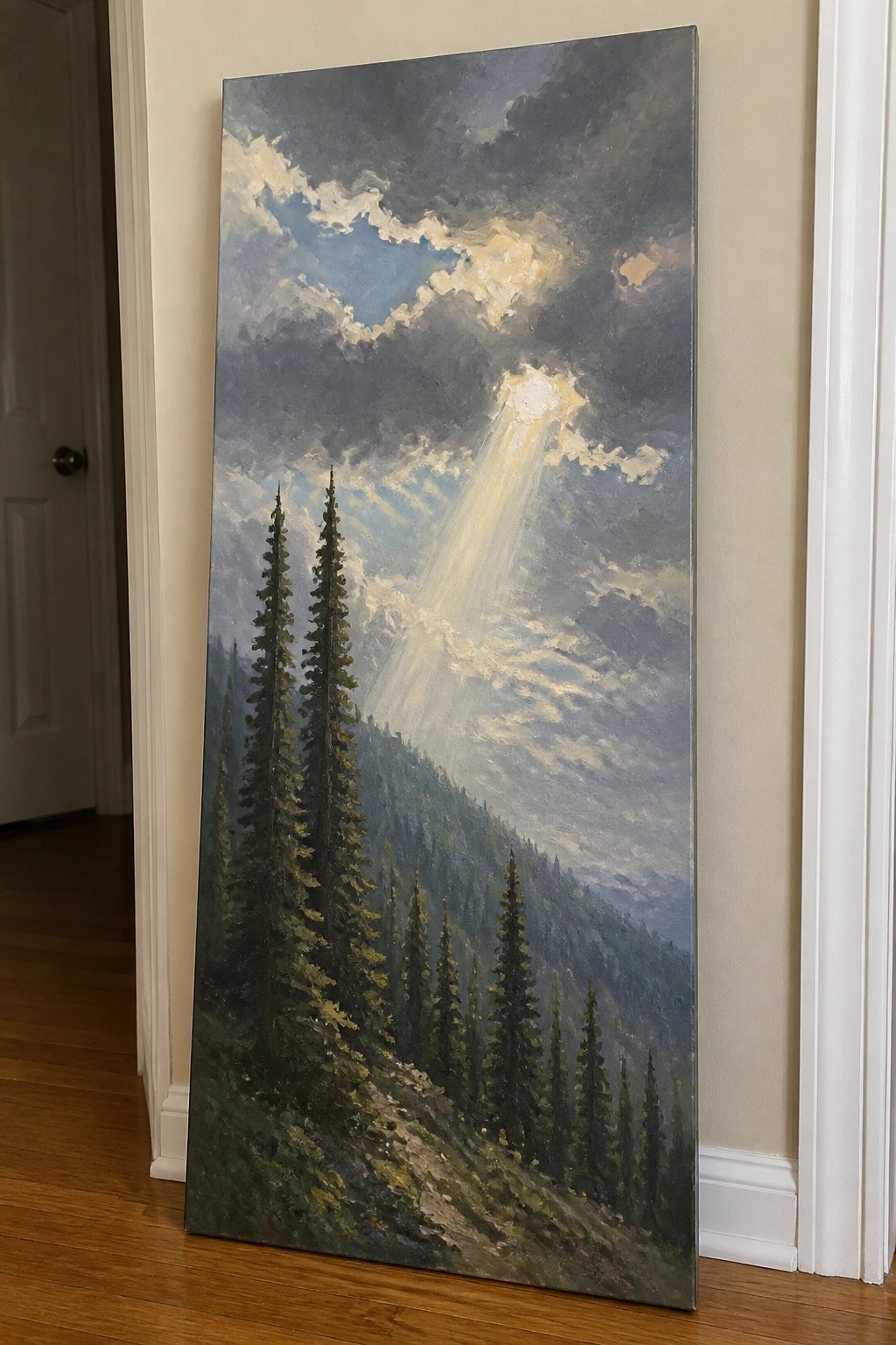 Large landscape painting of sunlit pines under cloudy sky leaning on wall.