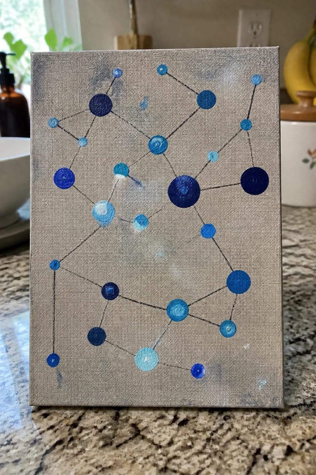 A small canvas with blue circles of varying sizes connected by thin black lines on a gray textured background.