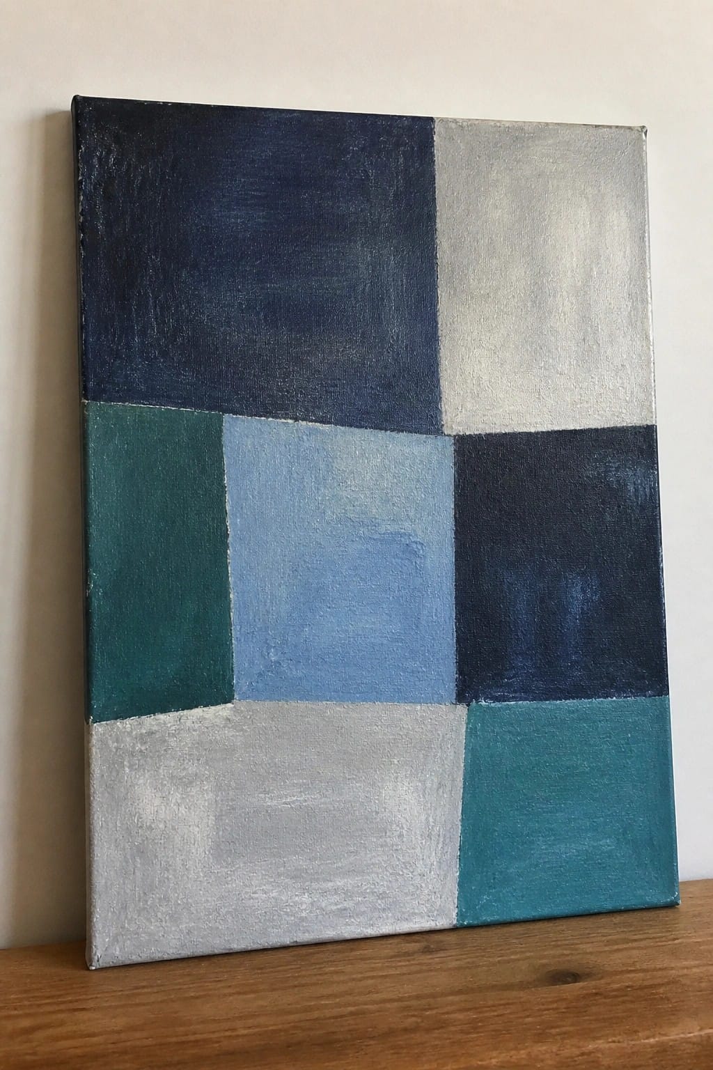 Abstract canvas painting with blocks of navy, teal, light blue, and gray.