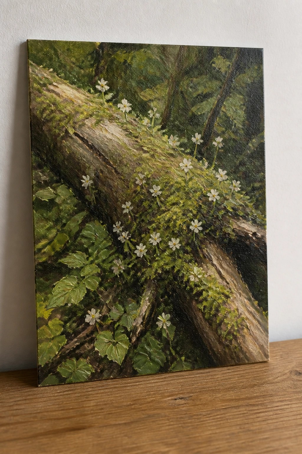 A realistic oil painting of a moss-covered fallen log with small white flowers growing along it in a forest.