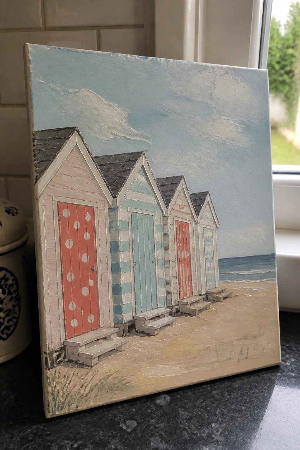 Colorful painting of five striped beach huts with red doors on sandy shore by sea