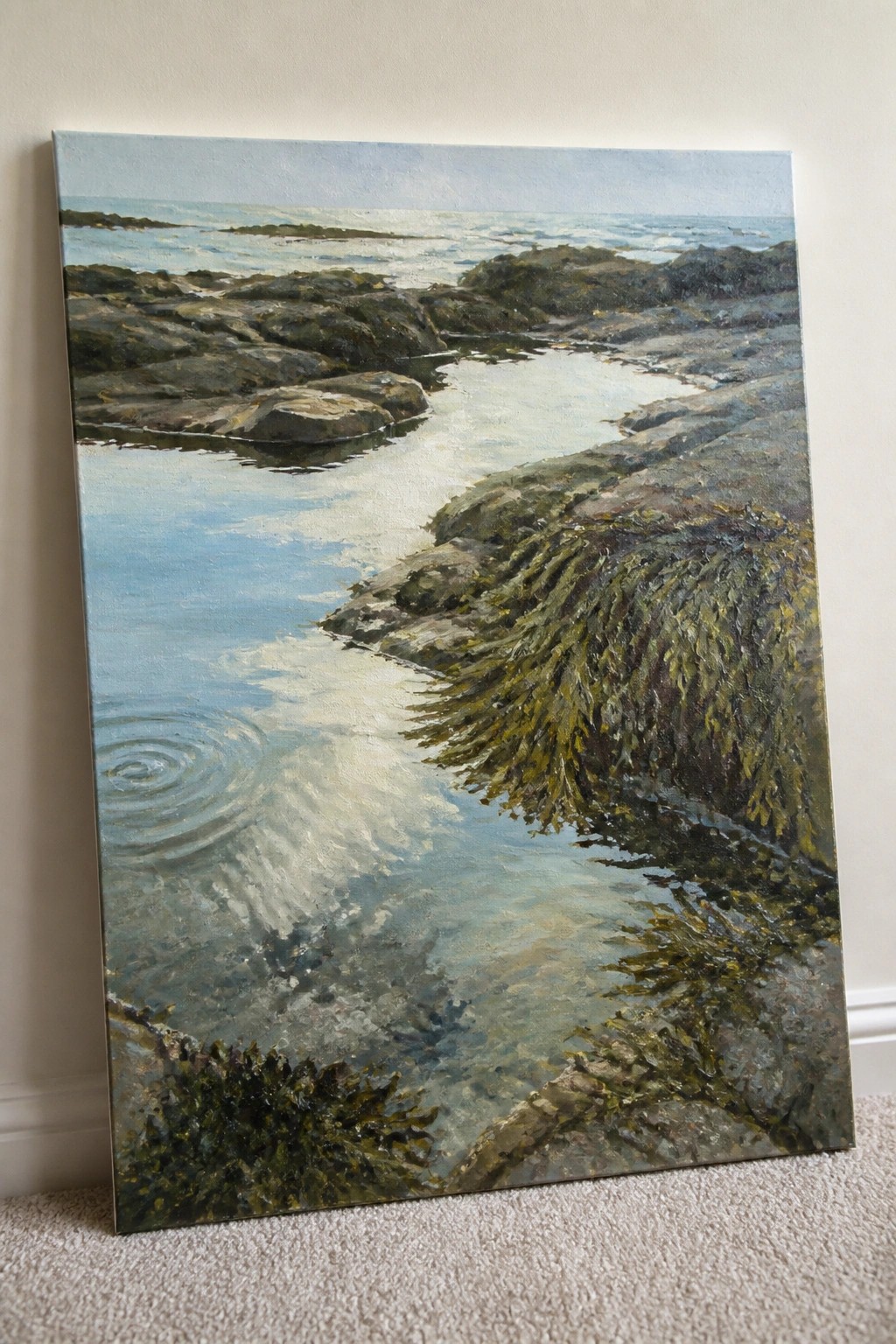 Seascape painting of rocky shore with green seaweed and calm blue water on carpet