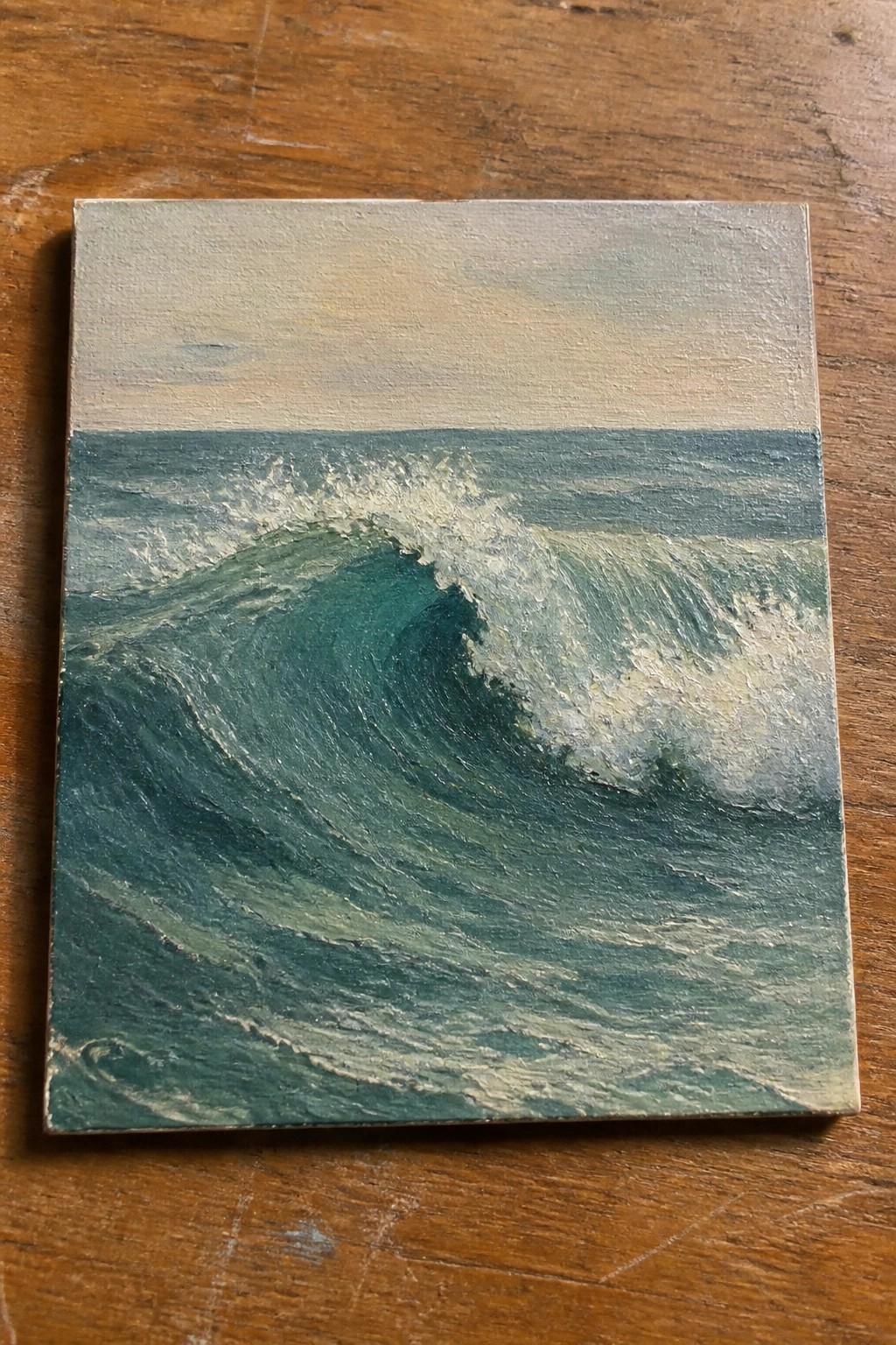 Realistic painting of a curling teal ocean wave with white foam on wood
