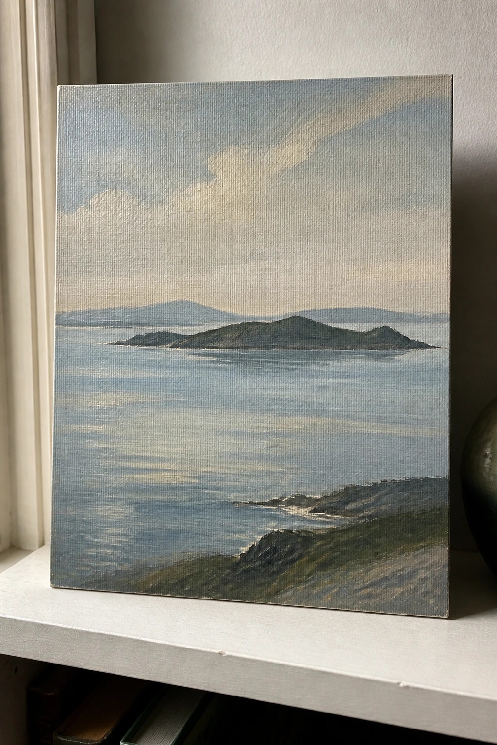 Seascape painting of calm blue waters with green islands on white ledge