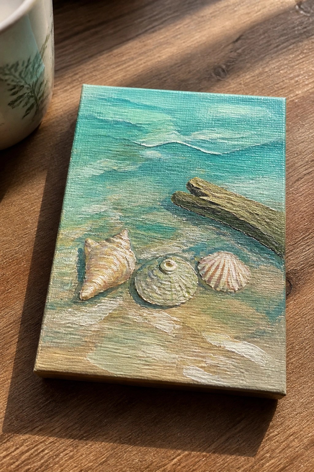 Small canvas painting of turquoise waves, sand, seashells, and driftwood.