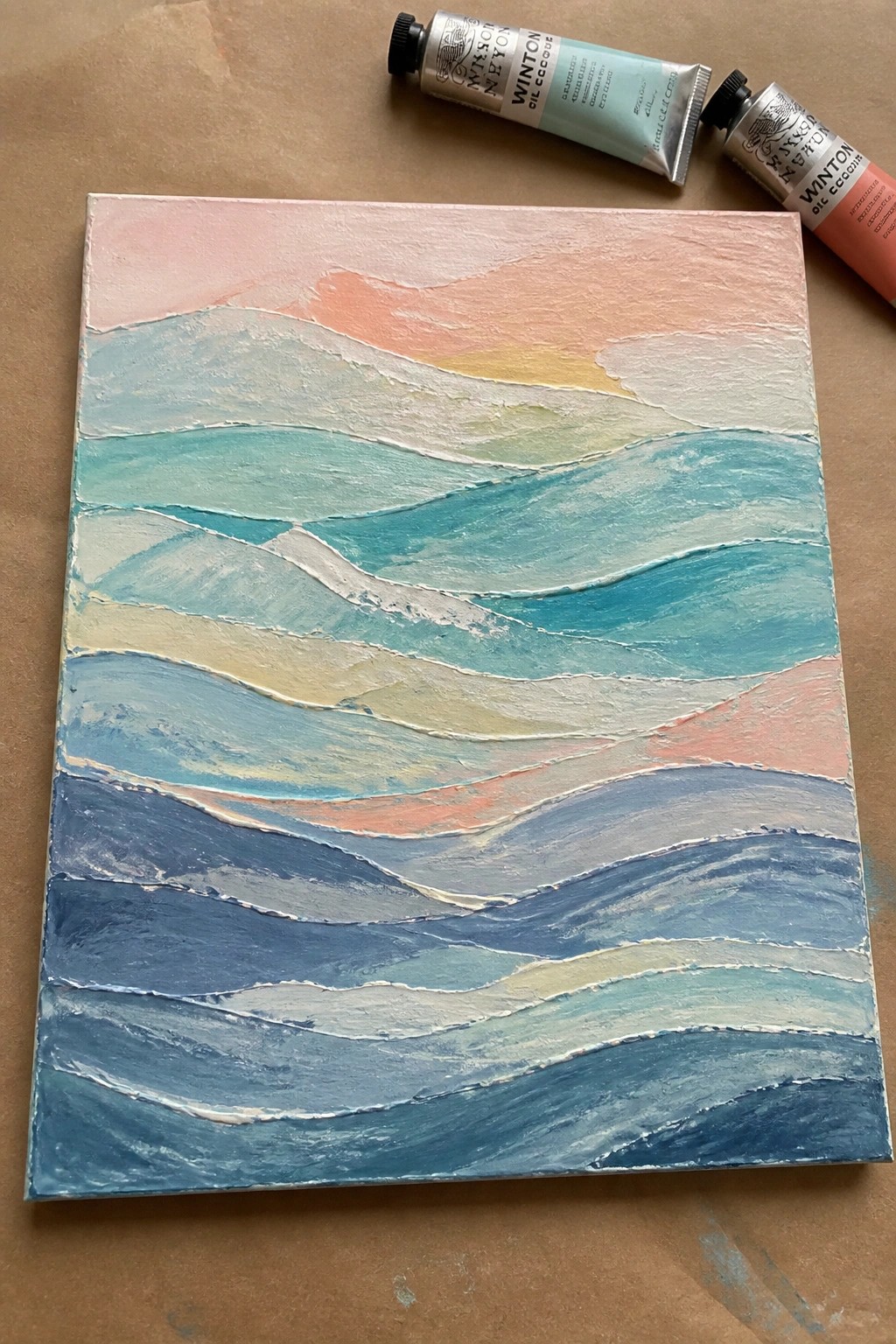 Pastel wave painting in blues and pinks with two Winton oil tubes