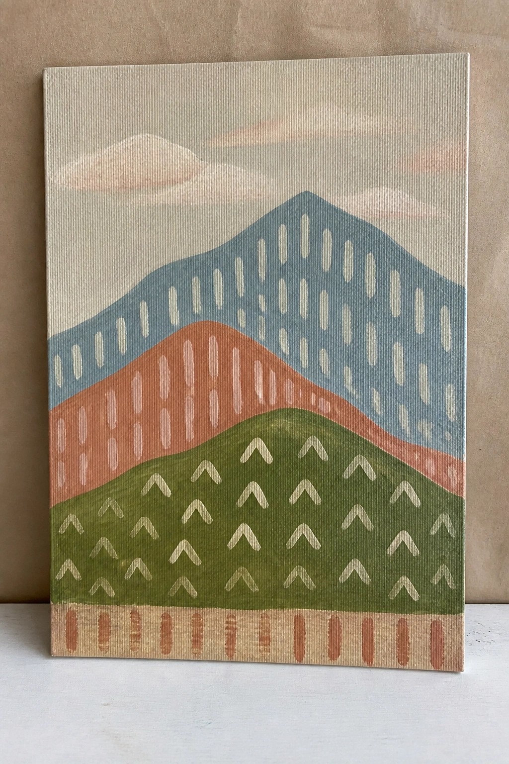 Abstract painting of layered hills in blue, orange, green with white patterns on beige sky.