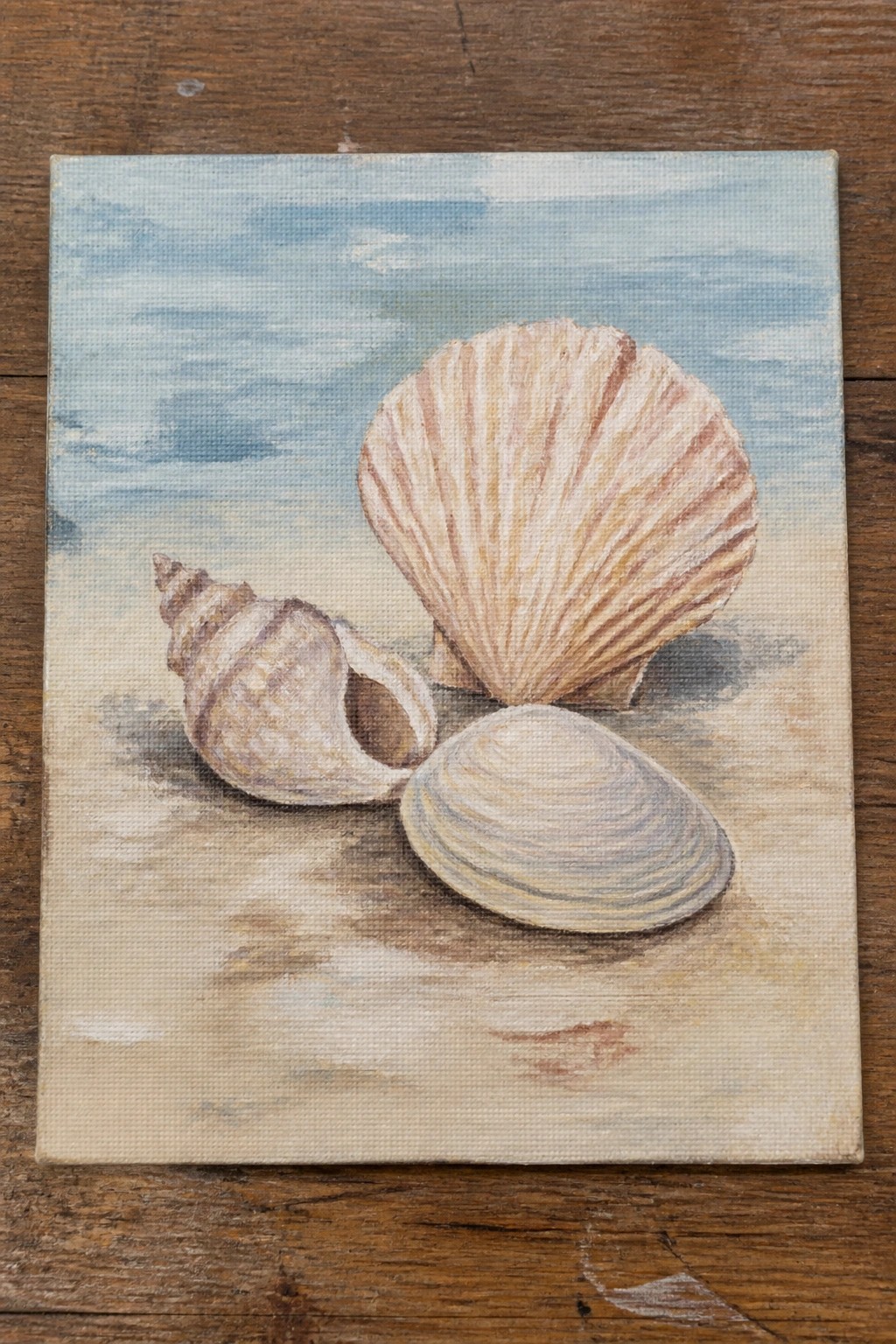 Three seashells on sandy beach under blue sky in canvas painting