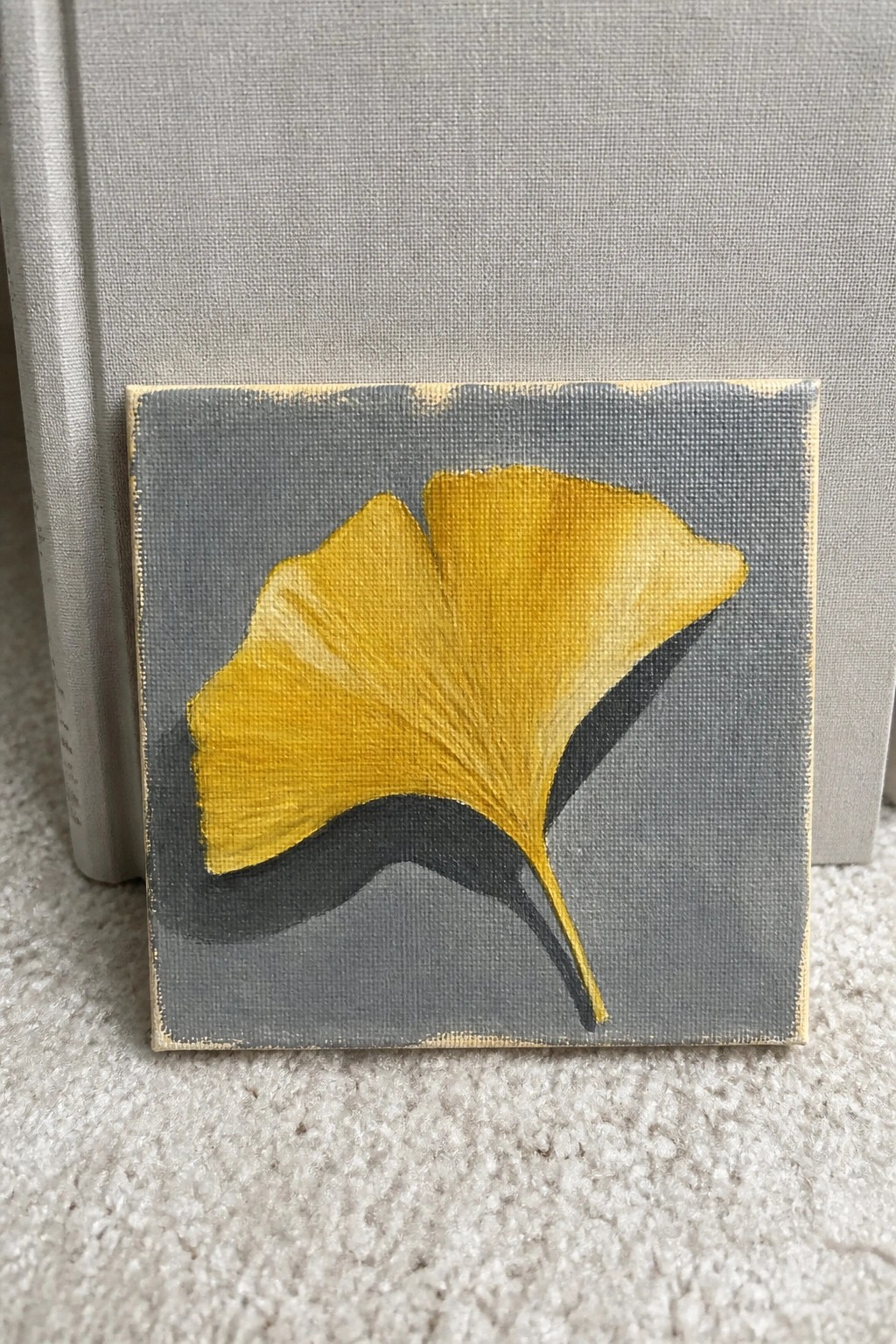 Yellow ginkgo leaf painting on gray square canvas against textured background