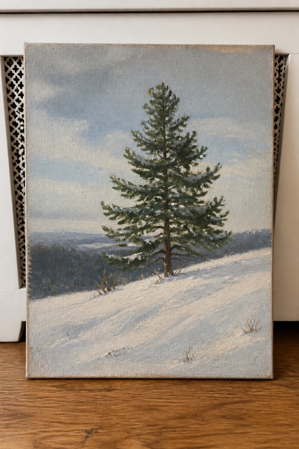 Realistic oil painting of lone pine tree on snowy hillside under cloudy sky.