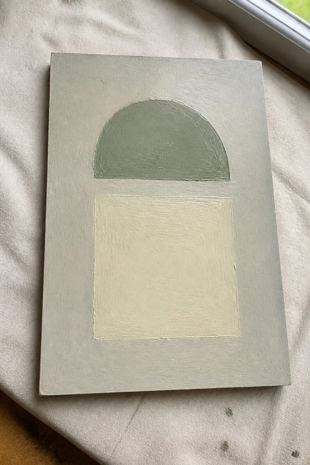 Abstract painting with green semicircle above pale yellow square on light gray canvas.
