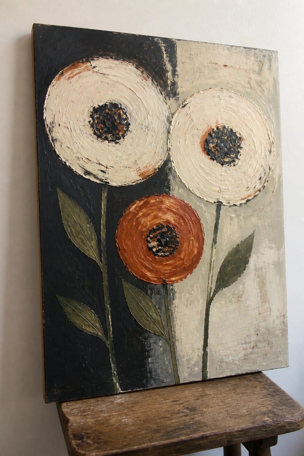 Abstract painting of three white and orange flowers on black-beige background atop wooden stool
