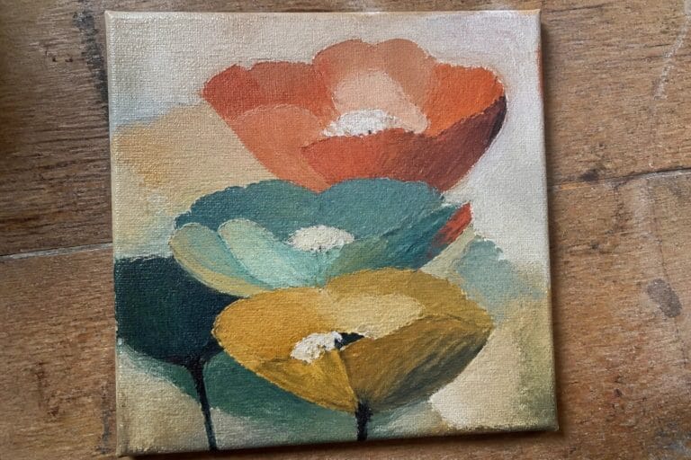 21 Modern Abstract Flower Oil Painting Ideas Using Expressive Color and Texture Abstract canvas painting of colorful overlapping circles forming flowers on wood table.