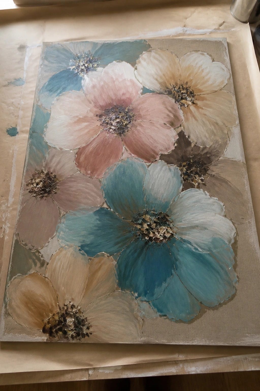 Textured abstract painting of large blue, pink, and beige flowers on canvas